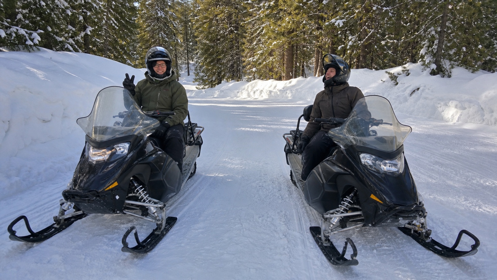 Two riders side by side on snowmobiles